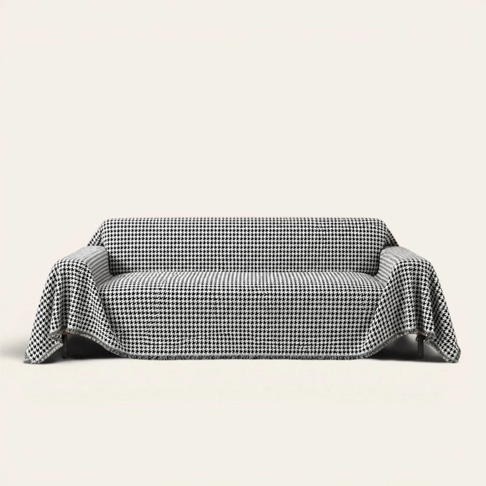 Midnight Hound Houndstitch sofa throw draped over a two-seat sofa, front view on ivory background, black and white houndstooth