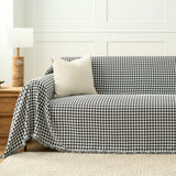 Midnight Hound Houndstitch throw styled on a sofa with a corduroy cushion and wooden lamp in a paneled room