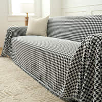 Midnight Hound Houndstitch throw over a sofa seat and arm with a fringed hem beside a floor lamp