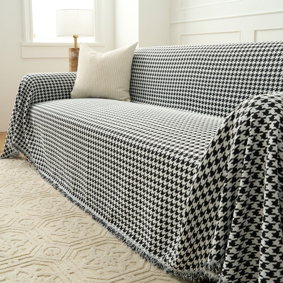 Midnight Hound Houndstitch throw over a sofa seat and arm with a fringed hem beside a floor lamp