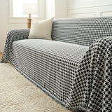 Midnight Hound Houndstitch throw over a sofa seat and arm with a fringed hem beside a floor lamp