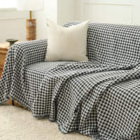 Midnight Hound Houndstitch throw draped over a sofa with a cream cushion, a fold cascading over the front