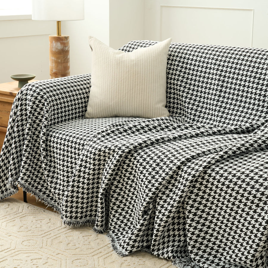 Midnight Hound Houndstitch throw draped over a sofa with a cream cushion, a fold cascading over the front