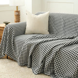 Midnight Hound Houndstitch throw draped over a sofa with a cream cushion, a fold cascading over the front