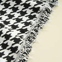 Close-up of Midnight Hound Houndstitch throw edge with a frayed fringe on an ivory surface