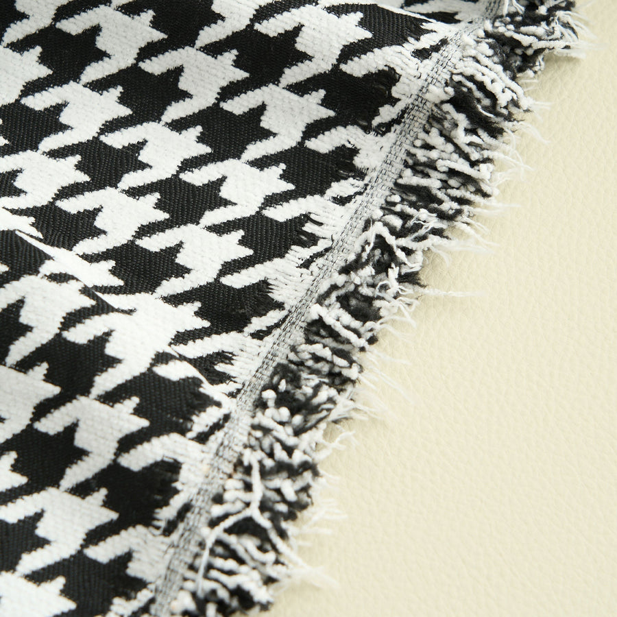 Close-up of Midnight Hound Houndstitch throw edge with a frayed fringe on an ivory surface