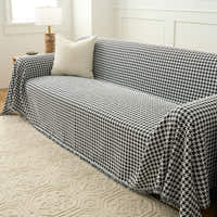 Angled view of Midnight Hound Houndstitch throw over a sofa, cascading over the arm onto a patterned rug