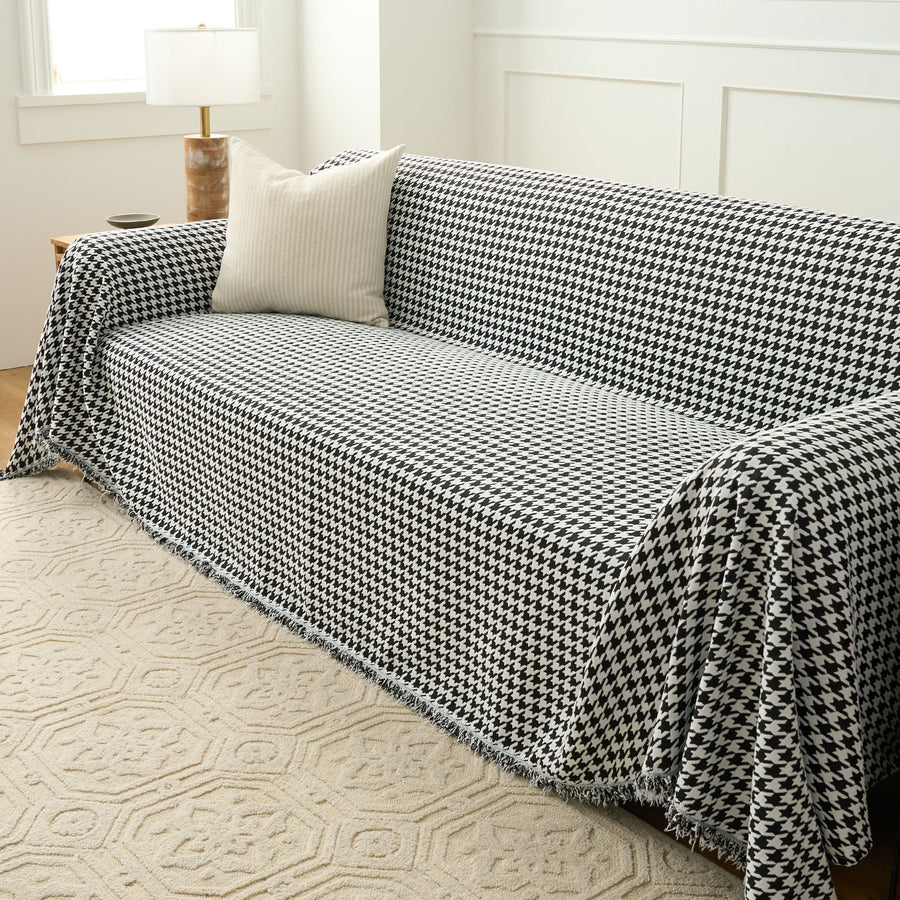 Angled view of Midnight Hound Houndstitch throw over a sofa, cascading over the arm onto a patterned rug