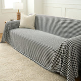 Angled view of Midnight Hound Houndstitch throw over a sofa, cascading over the arm onto a patterned rug