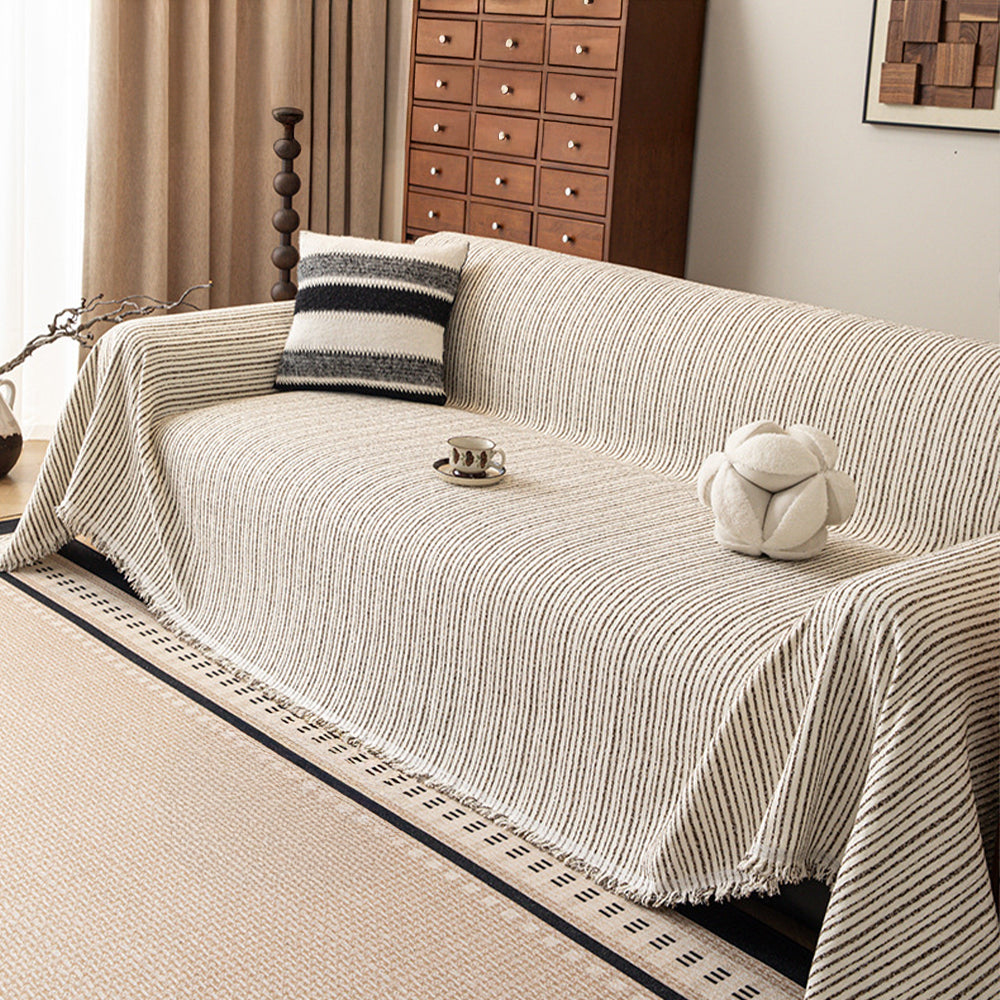 Charcoal Stripe Linear Weave throw covering a sofa with a striped cushion and coffee cup, wood cabinet in a living room