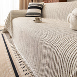 Charcoal Stripe Linear Weave throw on a sofa corner with striped cushion and coffee cup, close angled view with fringe