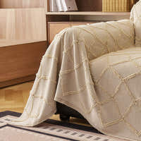 Oat Beige Luxe Diamond throw draped over the sofa arm beside a wood cabinet