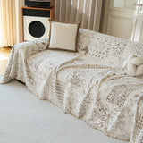 Angled view of the Luxe Heritage cream latte throw covering a sofa with a boucle cushion, patchwork motif