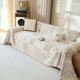 Cream latte Luxe Heritage throw on a couch in a warm living room with a cushion, tray and coffee cup