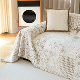 Close corner view of the Luxe Heritage cream latte throw draped over the sofa arm, woven patchwork motif