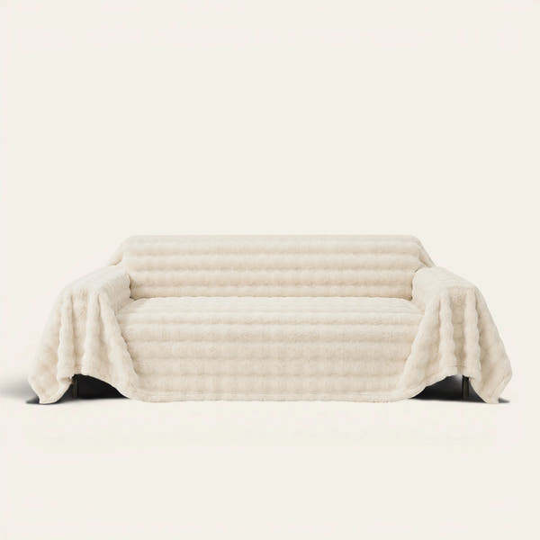 Luxe Ripple faux fur sofa throw in Ivory Luxe draped over a couch, front view on ivory background