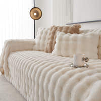 Ivory Luxe faux fur throw on a sofa with plush cushions and a cup, close angle view