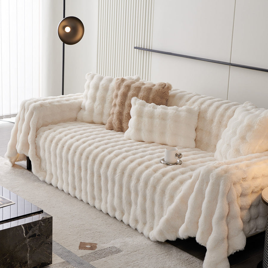 Luxe Ripple throw in Ivory Luxe over a sofa with cushions and pendant light, angle view
