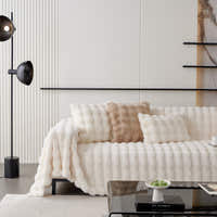 Ivory Luxe faux fur throw draped across a sofa with cushions in a bright styled room