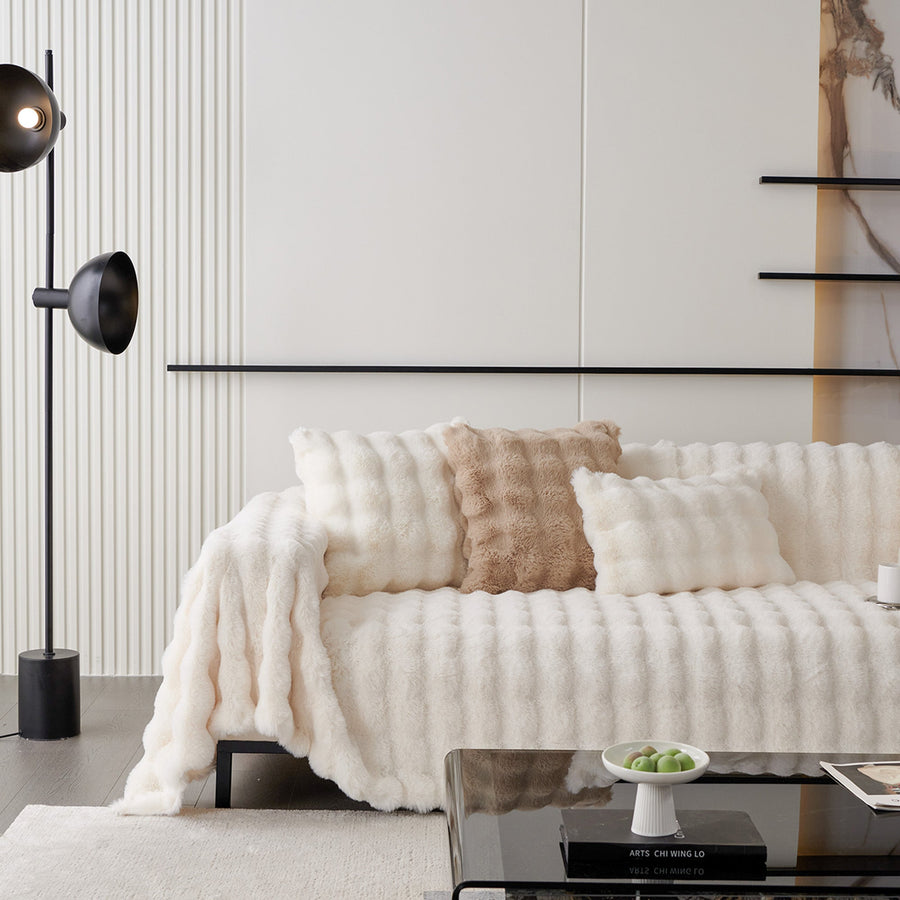 Ivory Luxe faux fur throw draped across a sofa with cushions in a bright styled room
