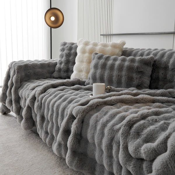 Smoky Quartz Luxe Ripple faux fur throw styled on a corner sofa with cushions and coffee