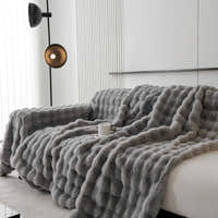 Angled cascade of the Smoky Quartz Luxe Ripple throw draped over a sofa