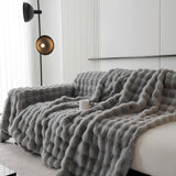 Angled cascade of the Smoky Quartz Luxe Ripple throw draped over a sofa