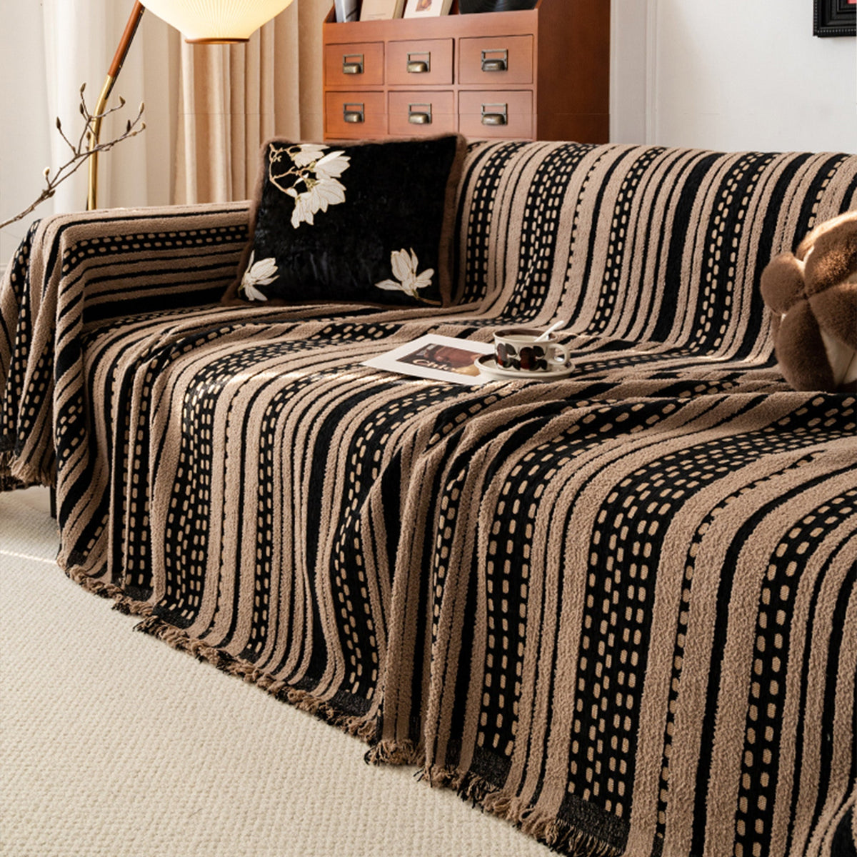 Cafe Noir Metro Stripe throw covering a sofa in a warm living room with wood cabinet, floral cushion and tray