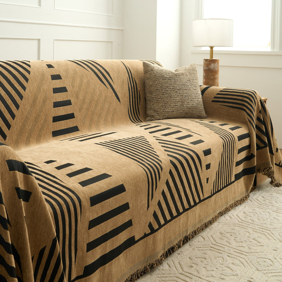 Modern jungle throw on a sofa with textured cushion and lamp near a window