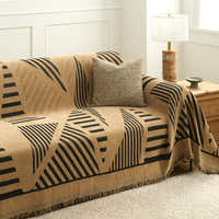 Modern jungle throw draped on a sofa with cushion, lamp and wood chest
