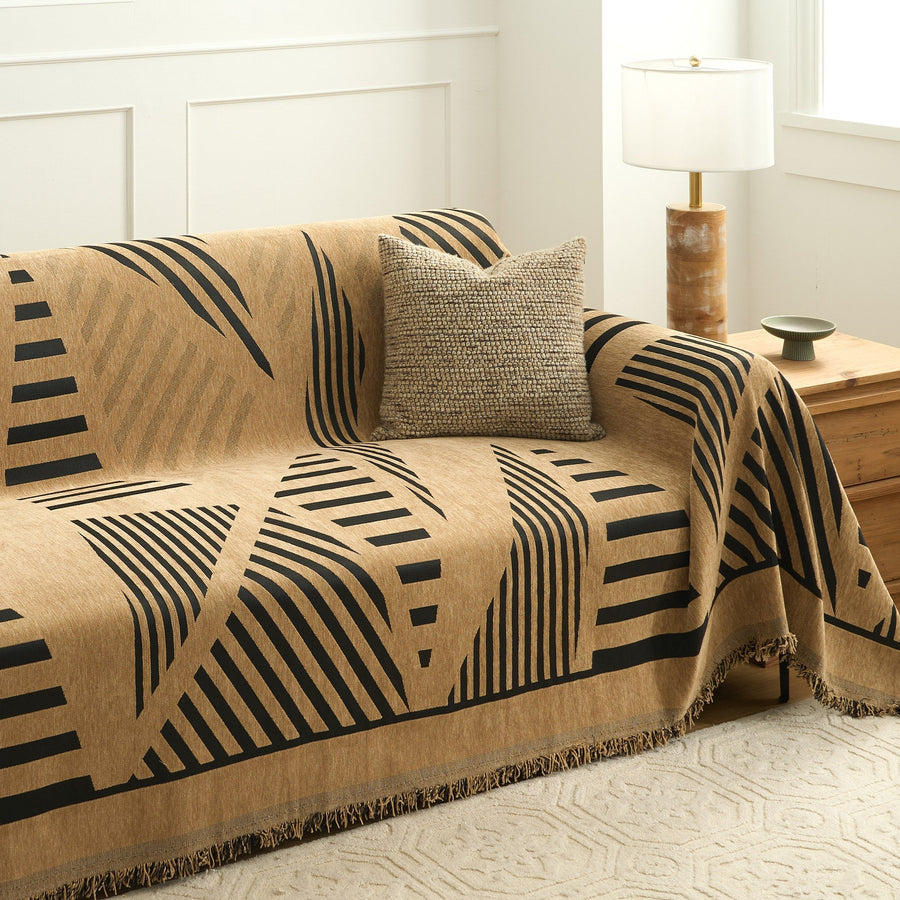 Modern jungle throw draped on a sofa with cushion, lamp and wood chest