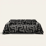 Charcoal Mist Modern Maze sofa throw draped over a three seater sofa, front view on ivory background with fringe