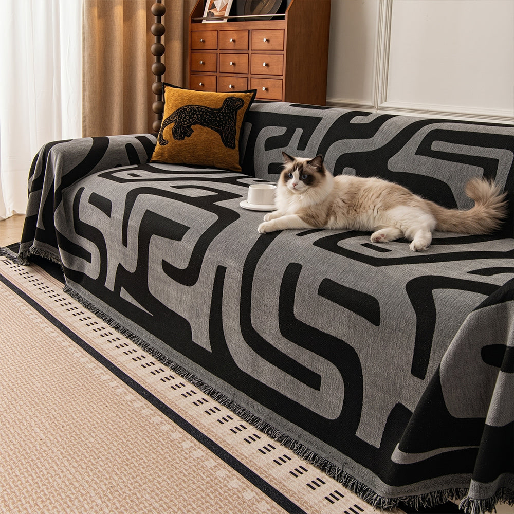 Charcoal Mist Modern Maze throw covering a sofa with a cat resting, leopard cushion and wood cabinet in a living room