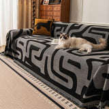 Charcoal Mist Modern Maze throw covering a sofa with a cat resting, leopard cushion and wood cabinet in a living room