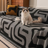 Charcoal Mist Modern Maze throw over a sofa with a fluffy cat and leopard cushion, angled view of the abstract pattern
