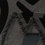 Macro close-up of Charcoal Mist Modern Maze throw showing the woven black and gray pattern and tasseled fringe
