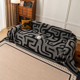 Overhead view of Charcoal Mist Modern Maze throw spread across a sofa with leopard cushion and coffee cup