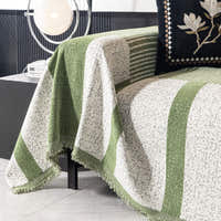 Close corner view of the forest green Modern Stripe throw draping over the sofa with a fringed hem