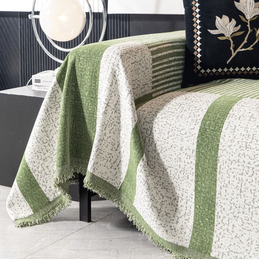 Close corner view of the forest green Modern Stripe throw draping over the sofa with a fringed hem