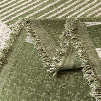 Detail of the forest green Modern Stripe throw's tasseled green fringe edge folded over