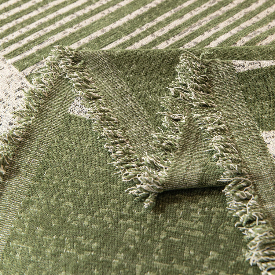 Detail of the forest green Modern Stripe throw's tasseled green fringe edge folded over