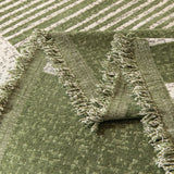 Detail of the forest green Modern Stripe throw's tasseled green fringe edge folded over