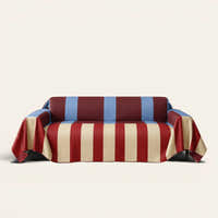 Modern Striped sofa throw in Brick Blue over a couch, front view with bold burgundy, cream and blue stripes