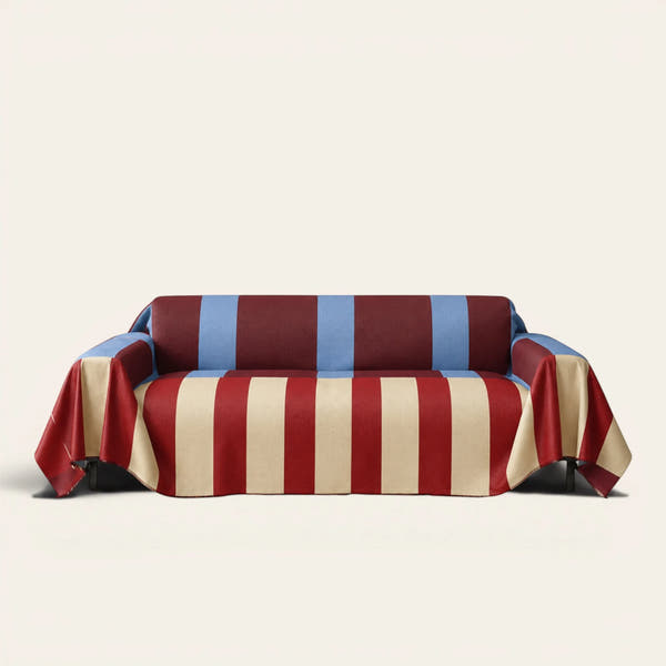 Modern Striped sofa throw in Brick Blue over a couch, front view with bold burgundy, cream and blue stripes