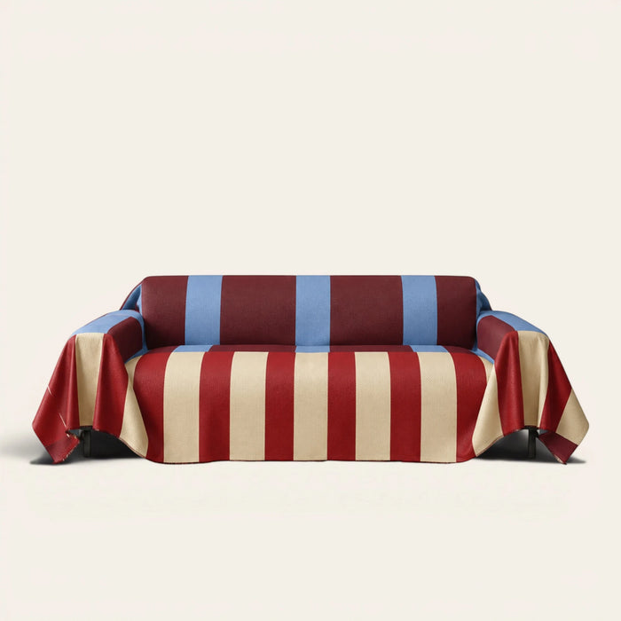 Modern Striped sofa throw in Brick Blue over a couch, front view with bold burgundy, cream and blue stripes