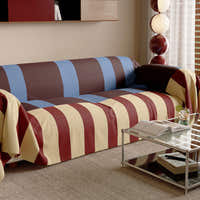Angled view of the Brick Blue Modern Striped throw on a sofa beside a glass table and lamp
