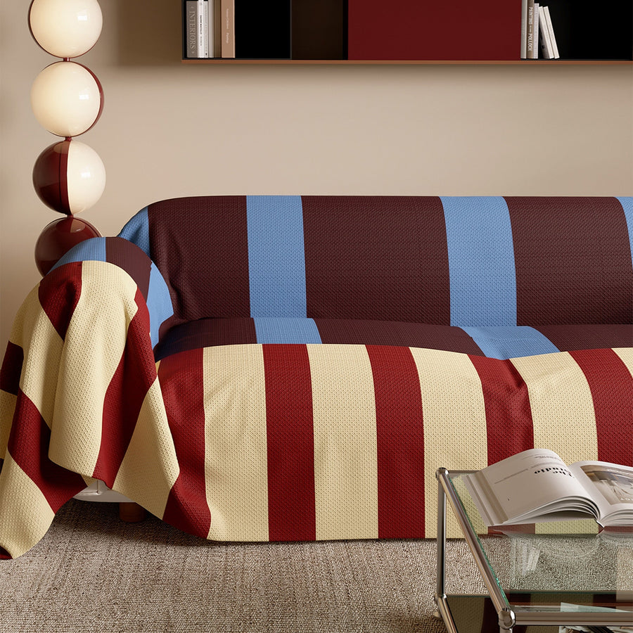 Brick Blue striped throw draped over a couch showing its reversible side by a bubble floor lamp