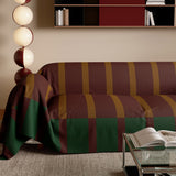 Close angled view of Brick Olive Modern Striped throw over the sofa arm showing the green bordered hem