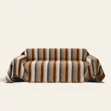 Caramel Sky Modern Striped sofa throw draped over a three seater sofa, front view on ivory background with fringed hem