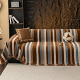Caramel Sky Modern Striped throw covering a sectional sofa against a stone wall with suede cushion and shelving
